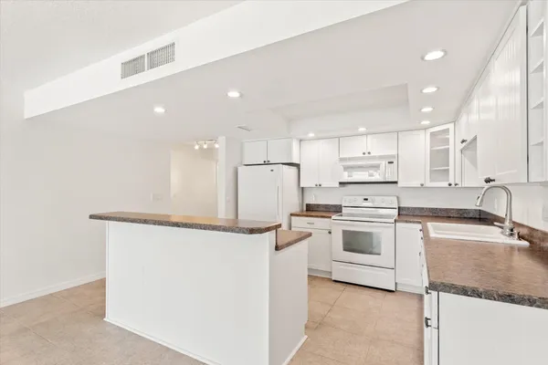 a kitchen with stainless steel appliances granite countertop a white stove top oven and white cabinets