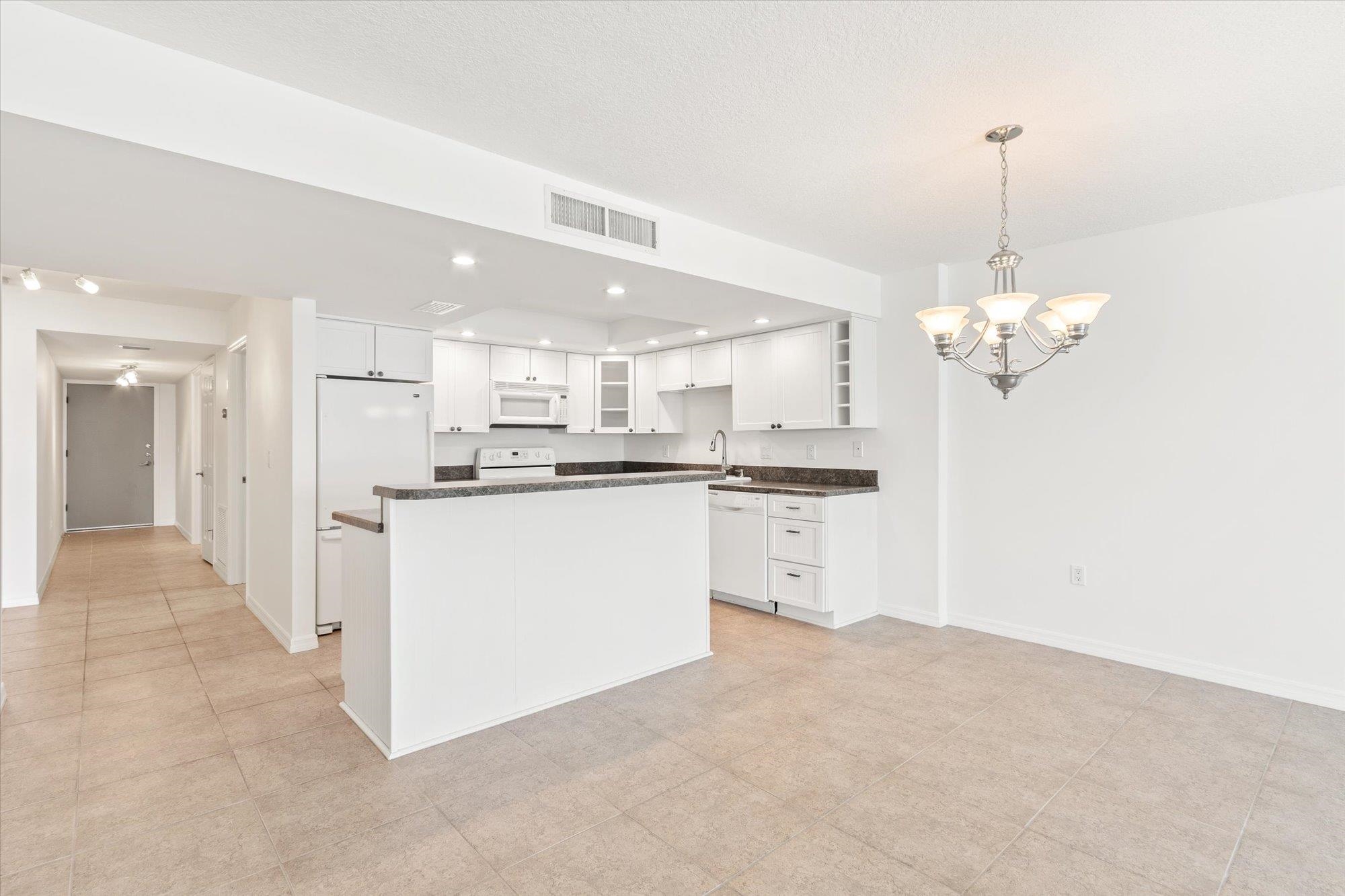 8090 A1A South, Unit 406 St. Augustine, FL 32080 - Photo 9 of 42 a kitchen with kitchen island white cabinets and refrigerator