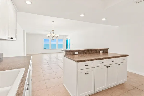 a view of a kitchen with kitchen island white cabinets and chandelier