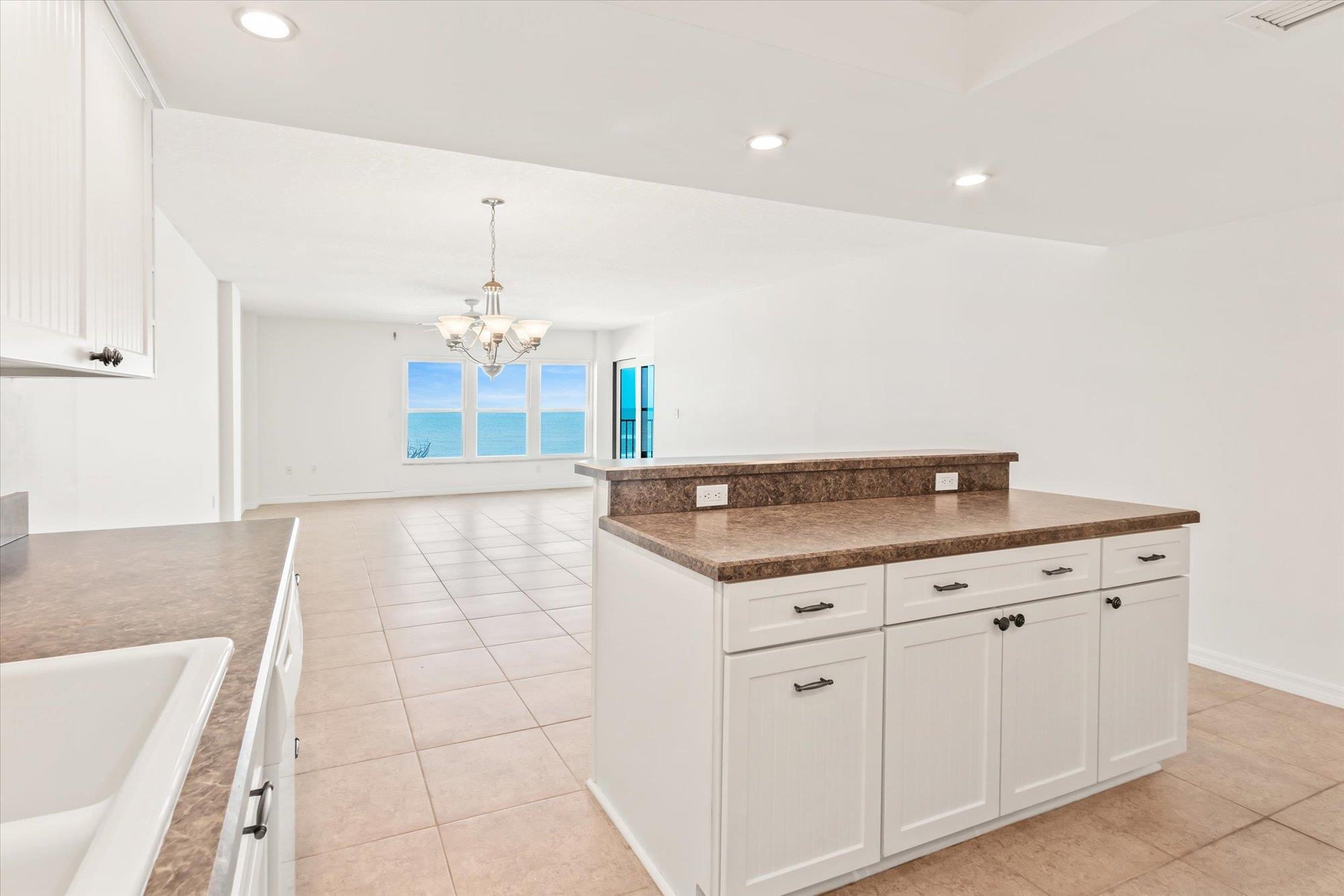 8090 A1A South, Unit 406 St. Augustine, FL 32080 - Photo 10 of 42 a view of a kitchen with kitchen island white cabinets and chandelier