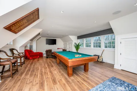 a room with wooden floor pool table and windows