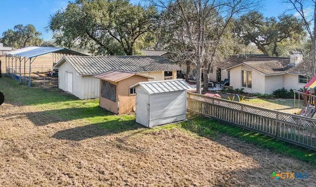a view of a house with a small yard and large trees