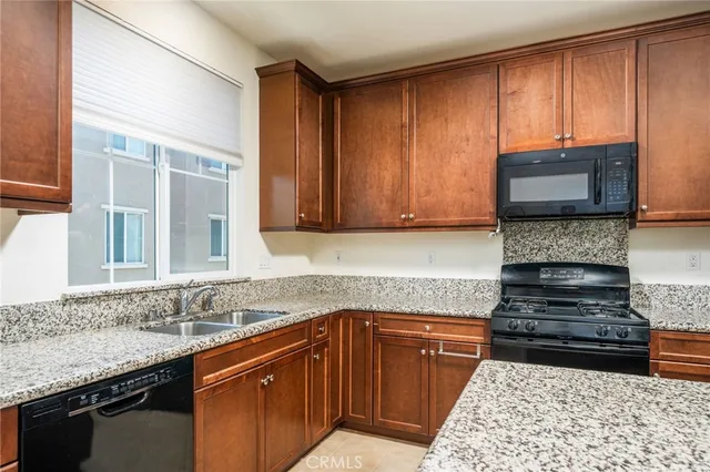 a kitchen with granite countertop stainless steel appliances a sink window and cabinets