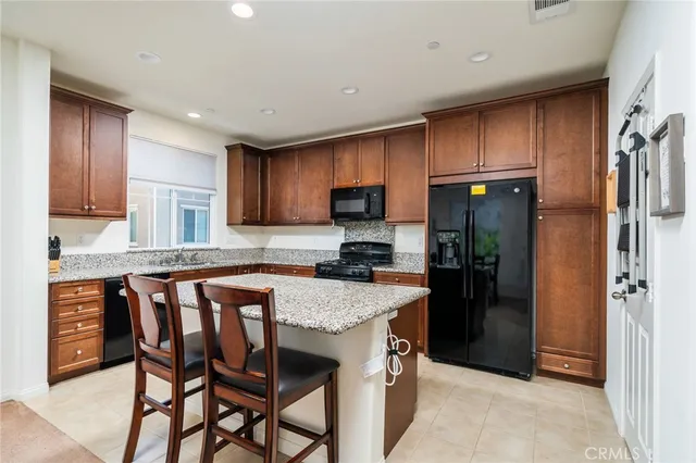a kitchen with granite countertop a refrigerator and wooden cabinets