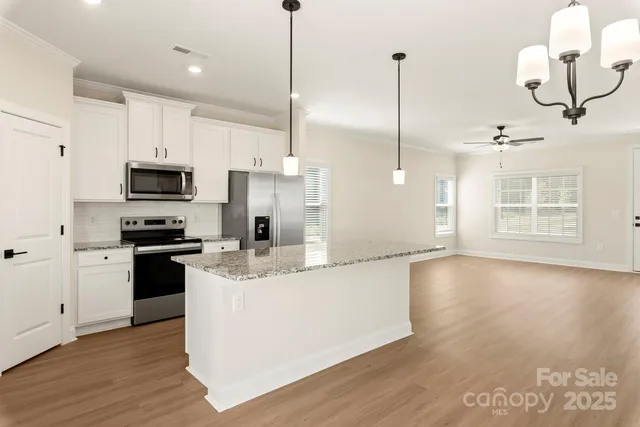 a kitchen with stainless steel appliances granite countertop a sink a stove a microwave and wooden floor