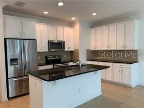 a kitchen with granite countertop a refrigerator stove and microwave