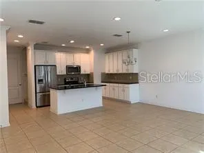 a kitchen with stainless steel appliances kitchen island granite countertop a stove a sink a refrigerator a microwave and cabinets