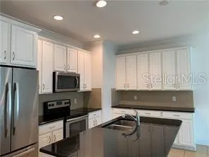 a kitchen with stainless steel appliances a stove a refrigerator a sink a stove a microwave and cabinets
