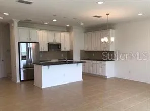 a large kitchen with stainless steel appliances granite countertop a refrigerator a stove a microwave and a sink