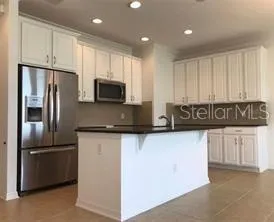 a kitchen with stainless steel appliances granite countertop a refrigerator a stove a sink and white cabinets