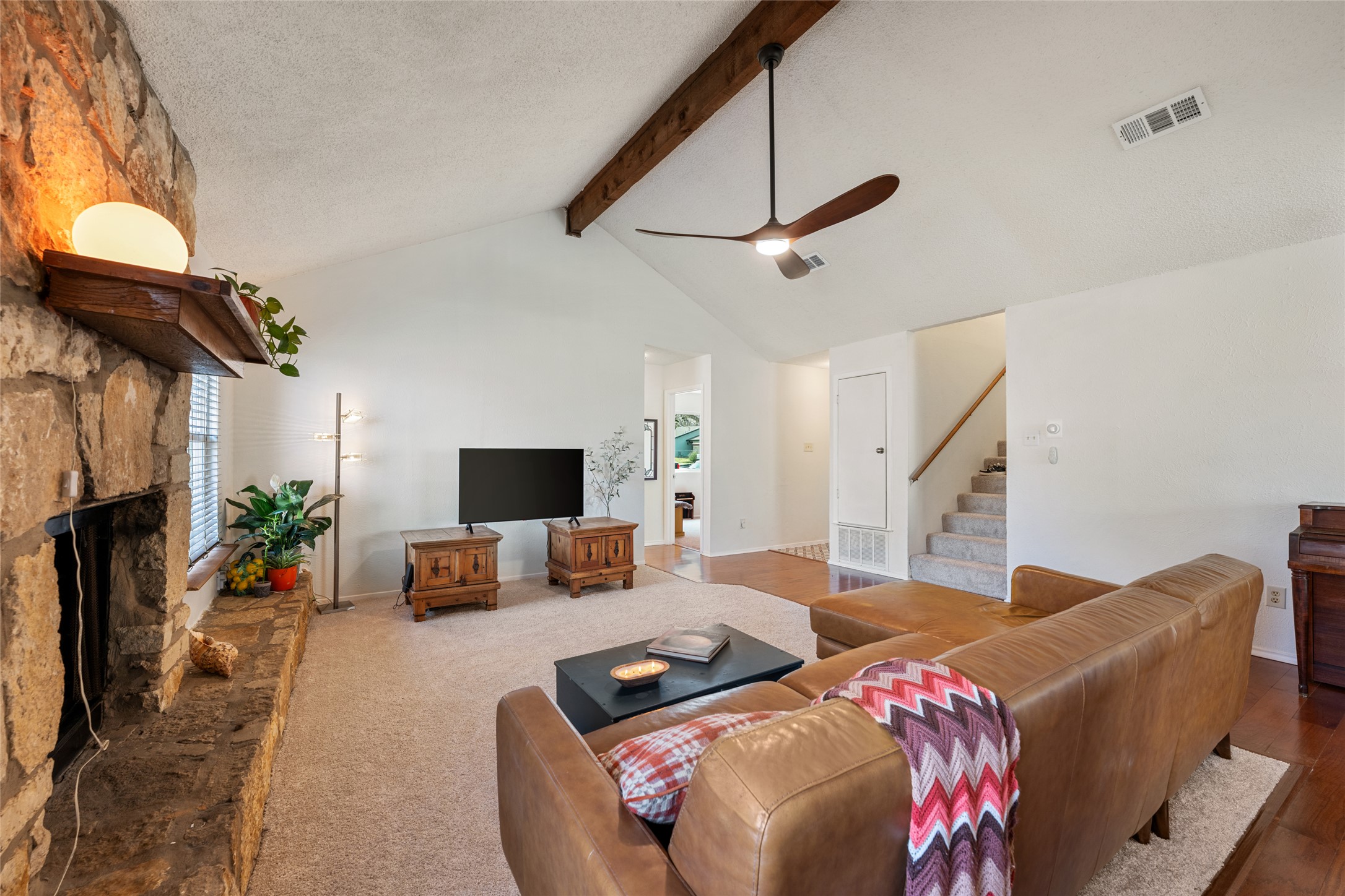5100 Lambs Lane Austin, TX 78744 - Photo 11 of 31 Living room featuring a stone fireplace, vaulted ceiling and a fan.