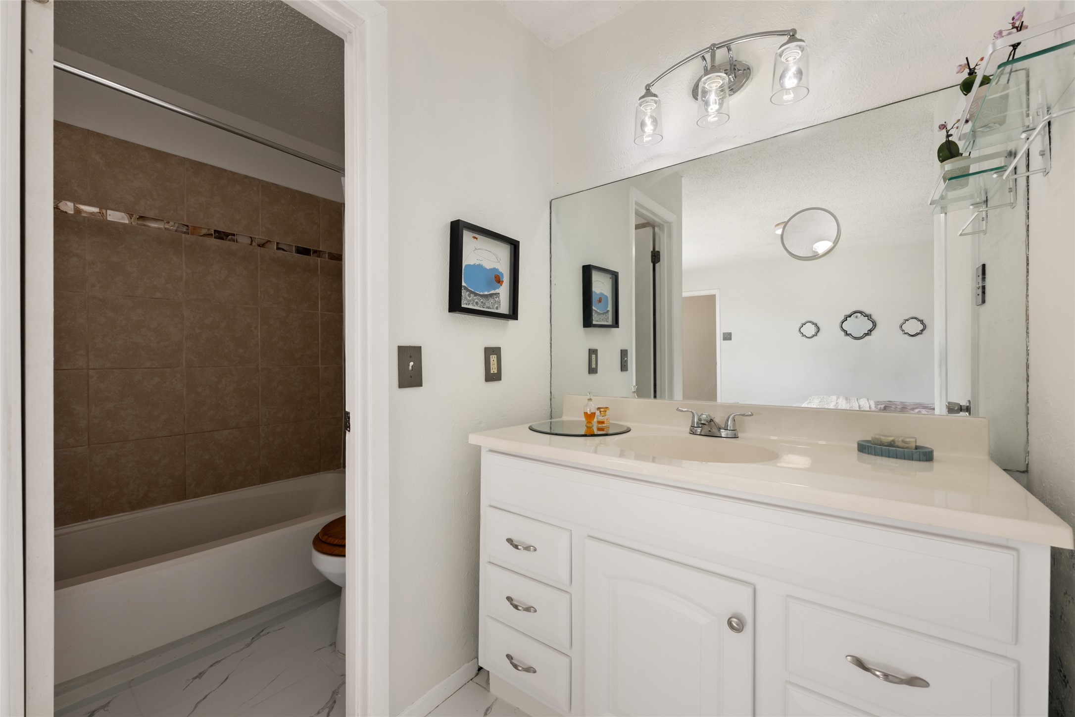 5100 Lambs Lane Austin, TX 78744 - Photo 24 of 31 Upstairs primary full bathroom off the primary bedroom, featuring vanity, shower / washtub combination, a textured ceiling, and light marble finish floors