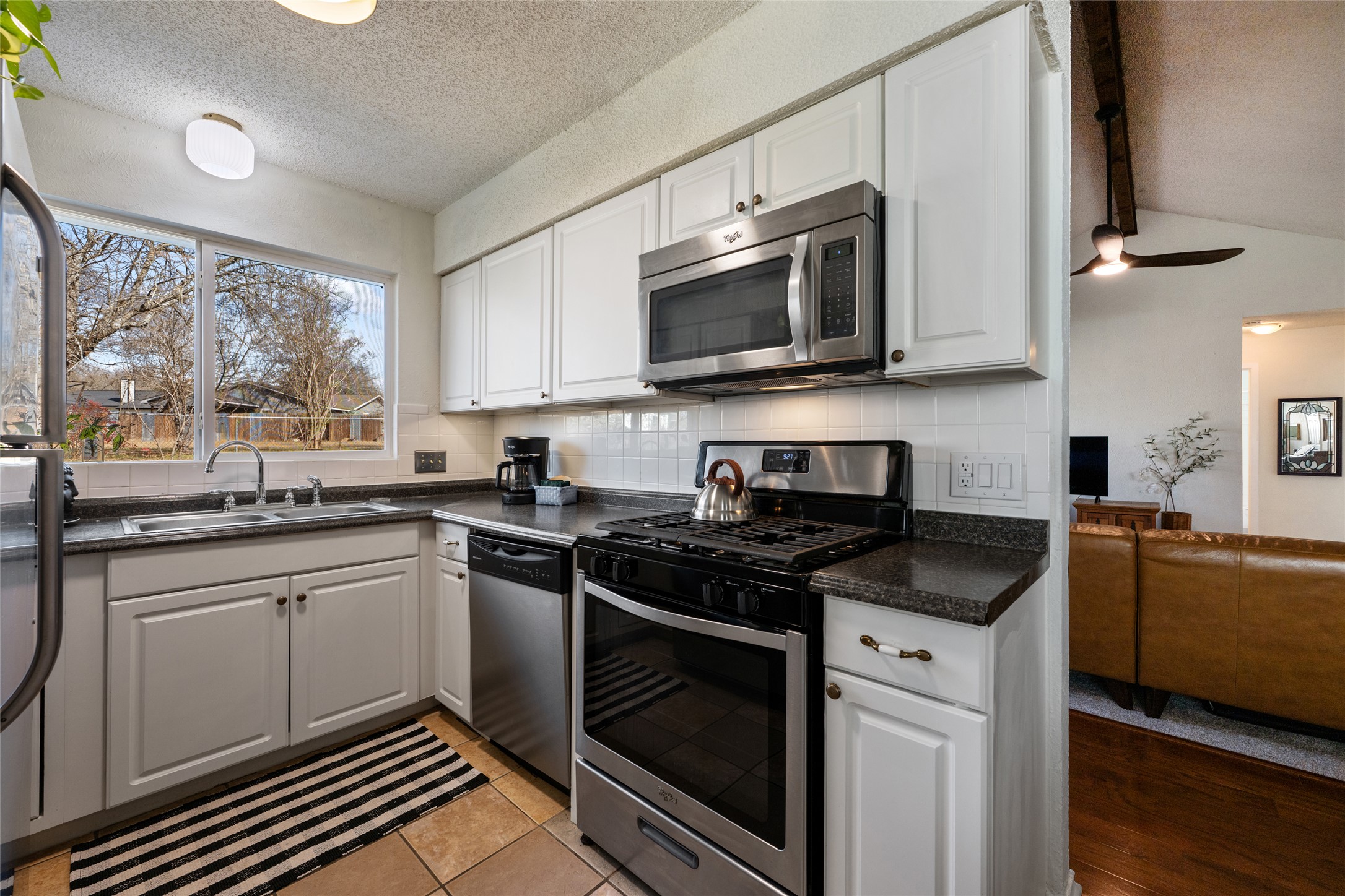 5100 Lambs Lane Austin, TX 78744 - Photo 3 of 31 Kitchen with stainless steel appliances, white cabinets, and light tile patterned floors