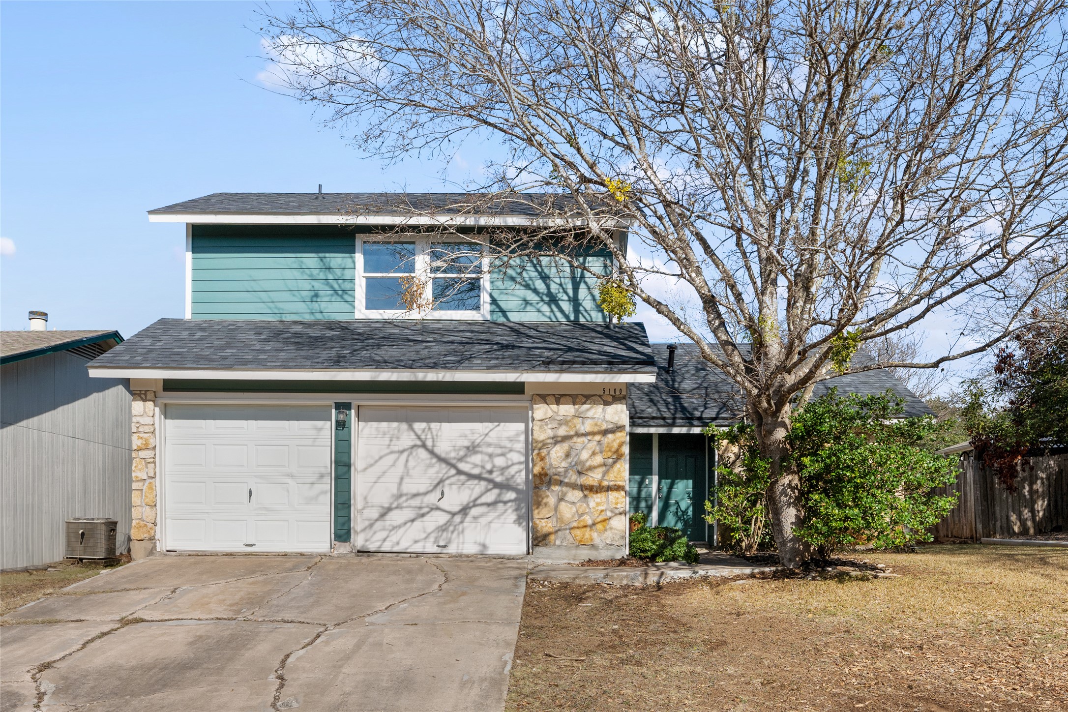 5100 Lambs Lane Austin, TX 78744 - Photo 5 of 31 View of front of house featuring stone and siding, a garage, driveway, and a shingled roof.