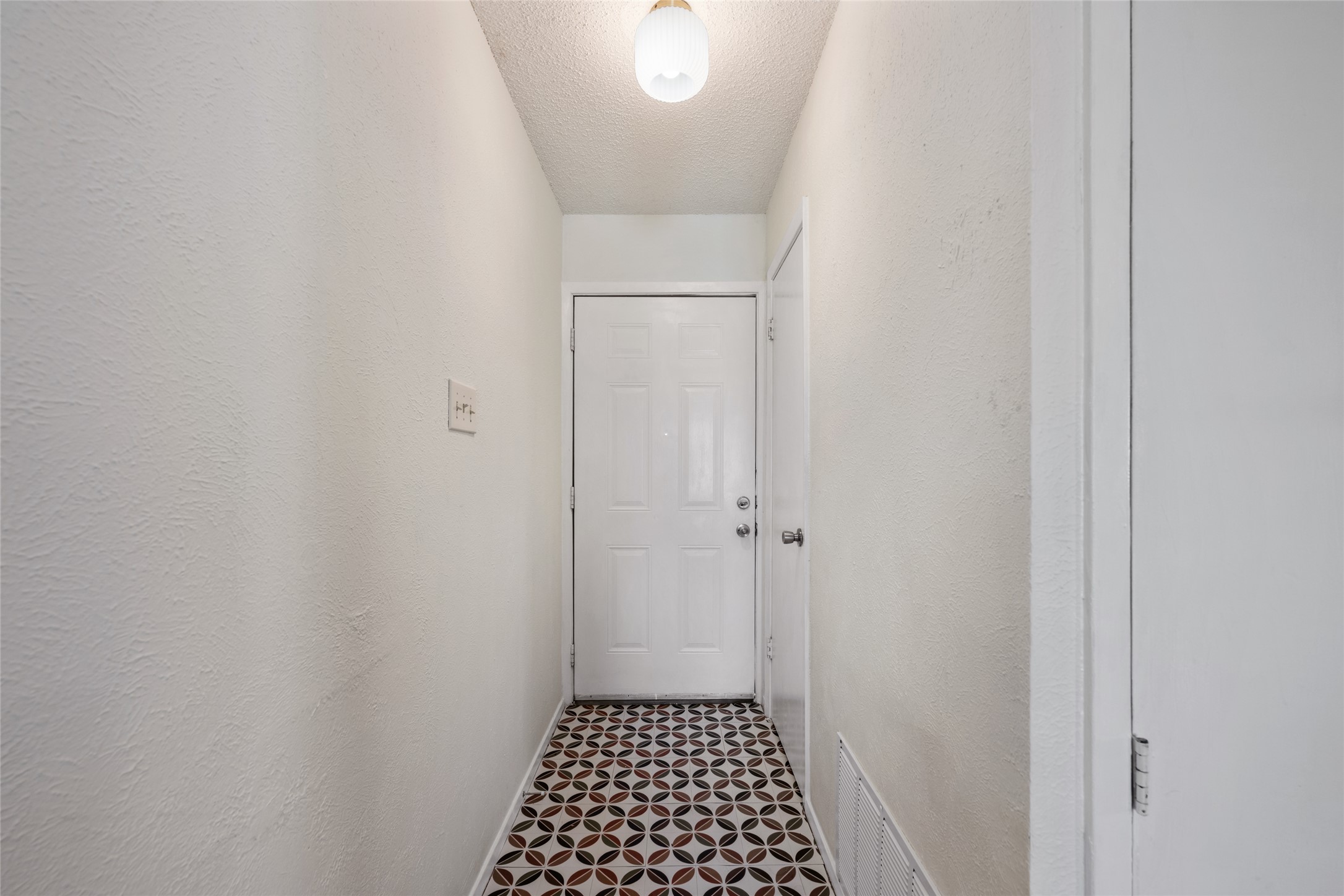 5100 Lambs Lane Austin, TX 78744 - Photo 7 of 31 Doorway to outside featuring a textured ceiling and a textured wall