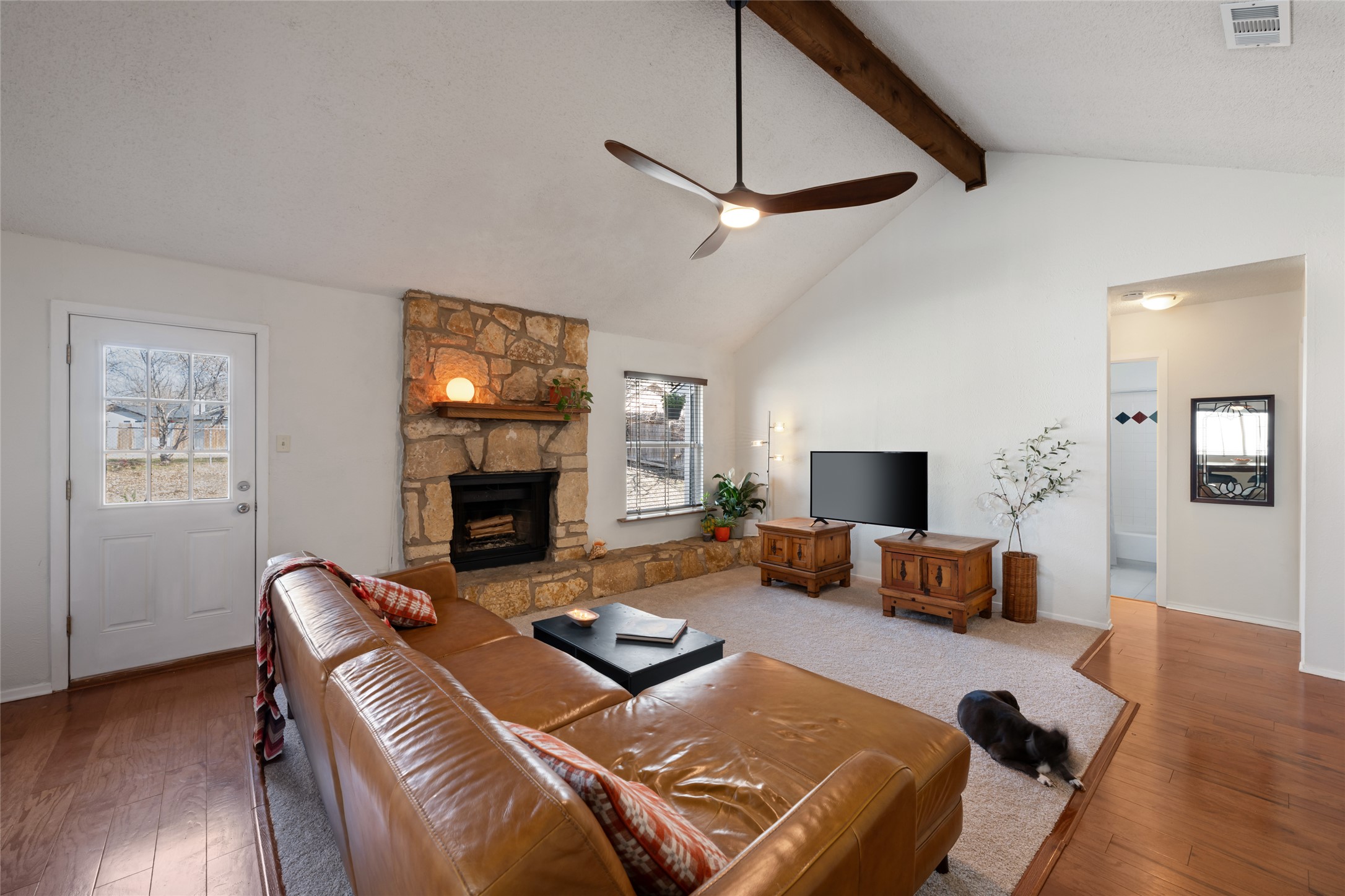5100 Lambs Lane Austin, TX 78744 - Photo 8 of 31 Living room with wood-style flooring, a stone fireplace, vaulted ceilling and fan.