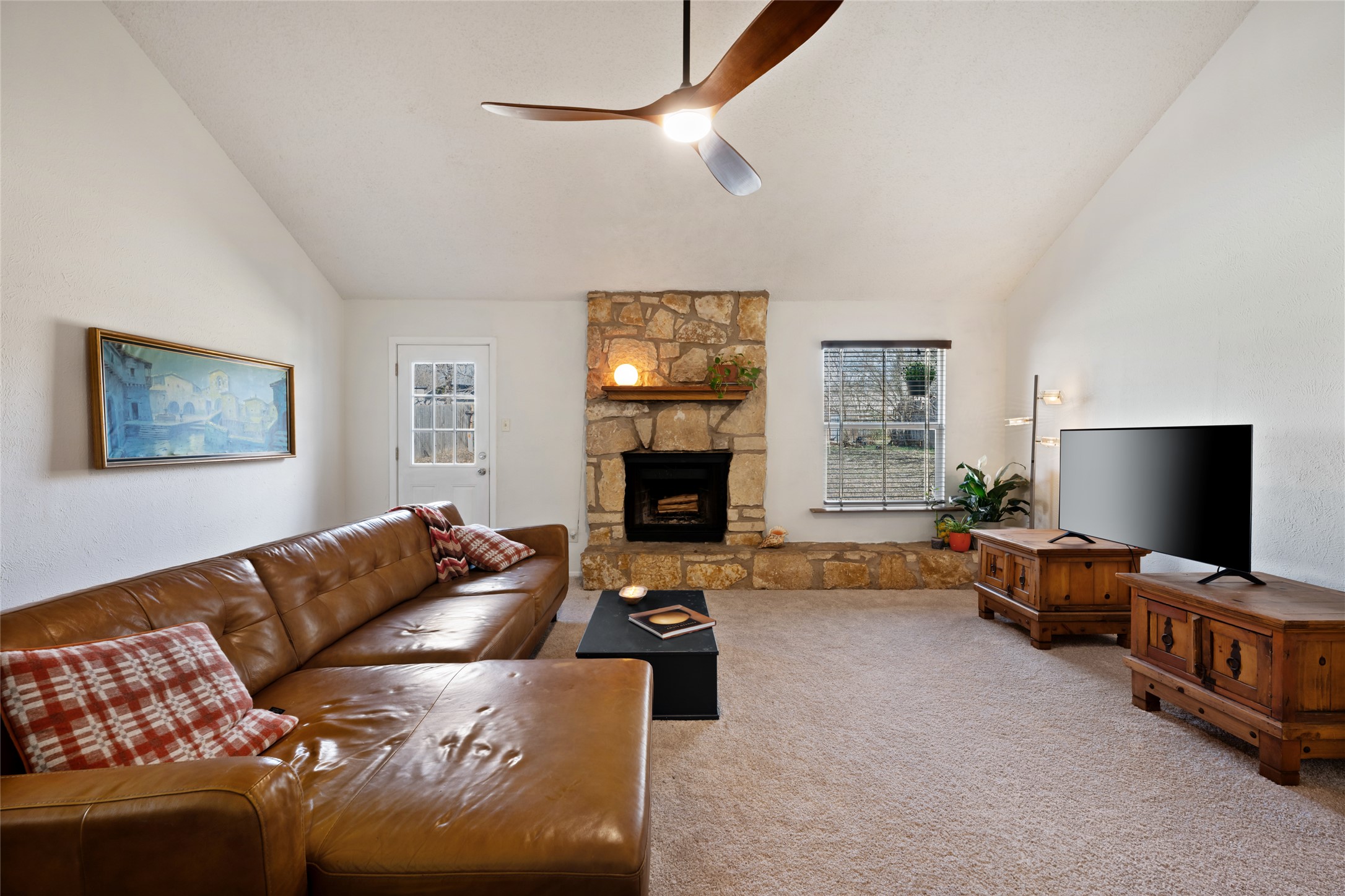 5100 Lambs Lane Austin, TX 78744 - Photo 9 of 31 Living area with vaulted ceiling, a cozy stone fireplace, and ceiling fan.