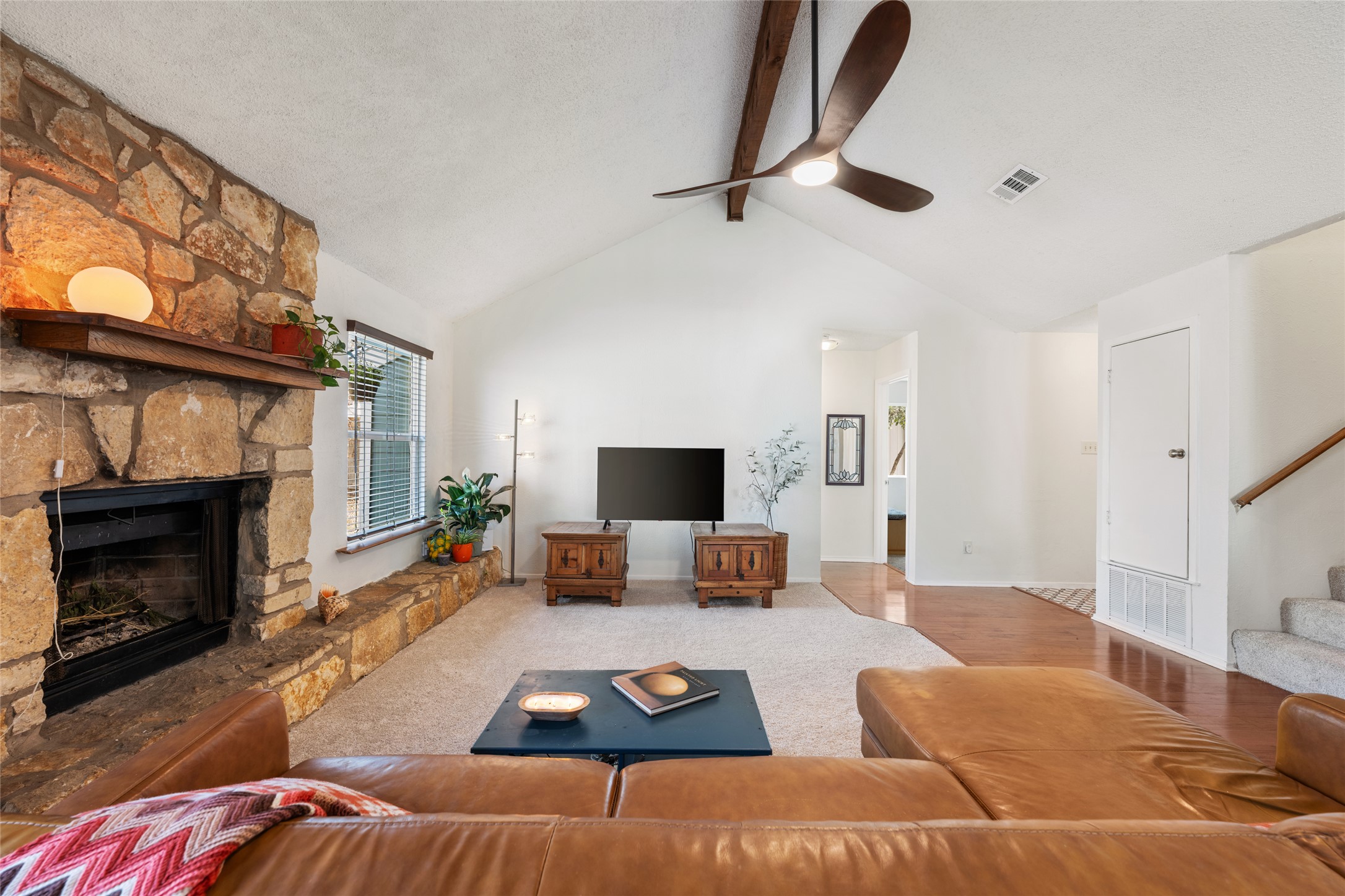 5100 Lambs Lane Austin, TX 78744 - Photo 10 of 31 Living room with a stone fireplace, vaulted ceiling and a fan.