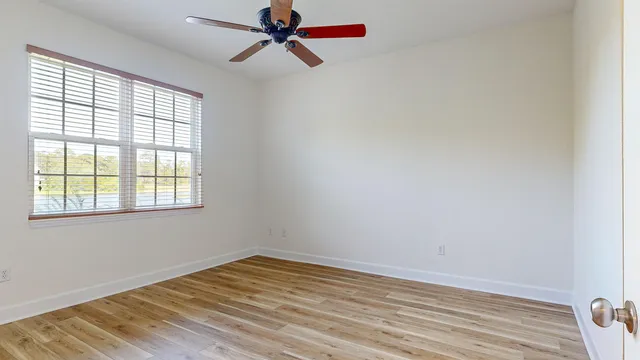 a view of empty room with wooden floor and fan