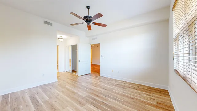 an empty room with wooden floor and ceiling fan