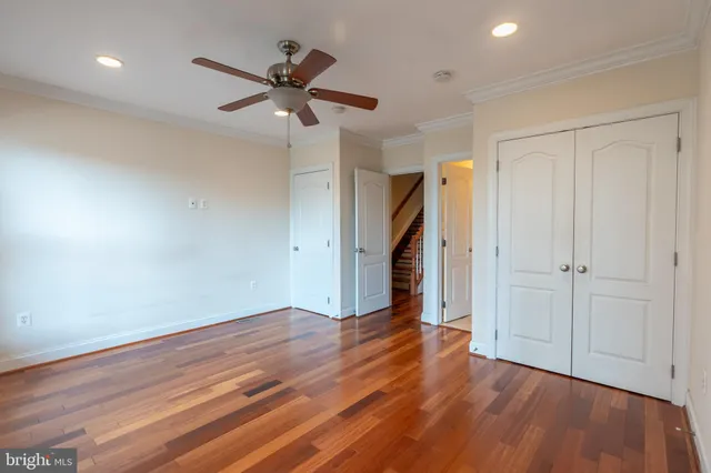 an empty room with wooden floor a ceiling fan and windows