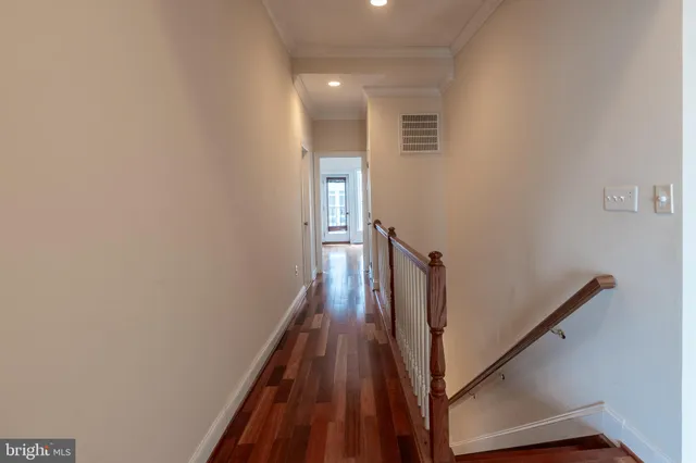 a view of a hallway with wooden floor and staircase