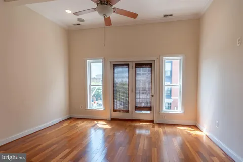 an empty room with wooden floor and windows