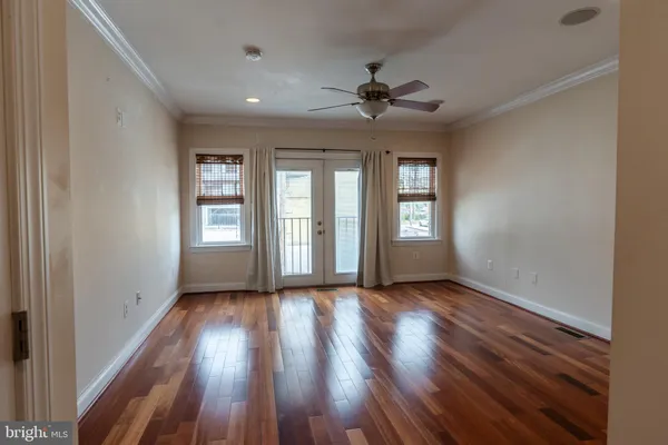 a view of an empty room with wooden floor and a window