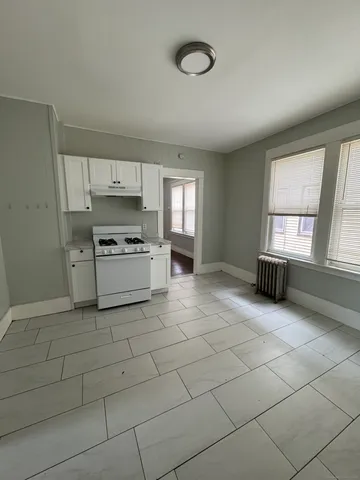 a kitchen with granite countertop a stove a sink and a refrigerator