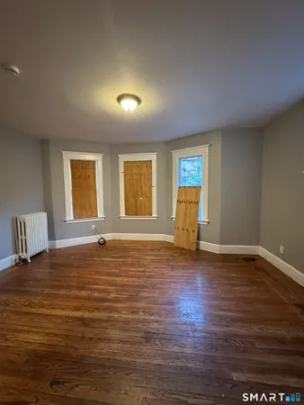 a view of an empty room with window and wooden floor