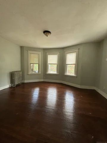 an empty room with wooden floor and windows with curtains