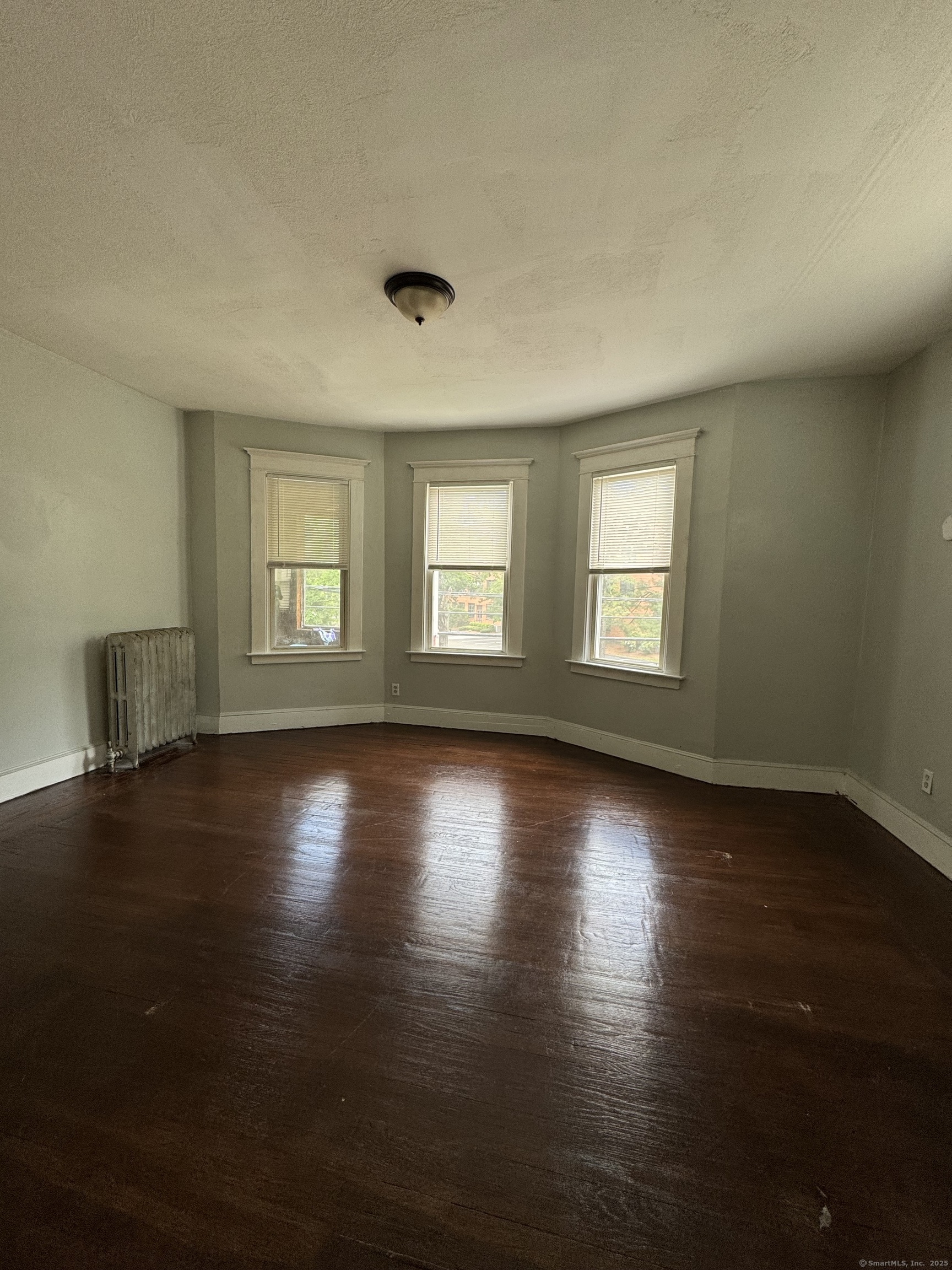 916 Winchester Avenue, Unit 1 New Haven, CT 06511 - Photo 5 of 10 an empty room with wooden floor and windows with curtains