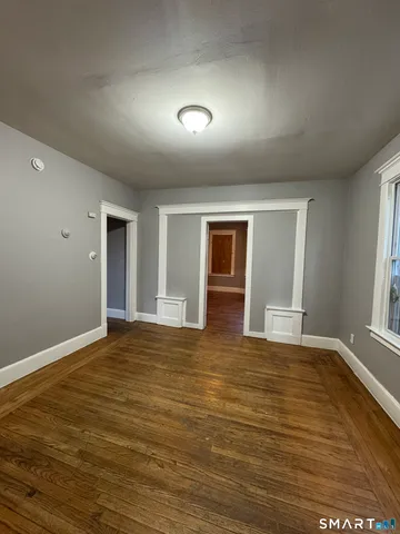 a view of an empty room with window and wooden floor