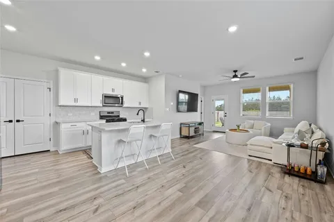 a large white living room with stainless steel appliances granite countertop a couch and a view of living room
