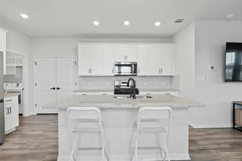 a kitchen with a sink a stove a refrigerator and white cabinets