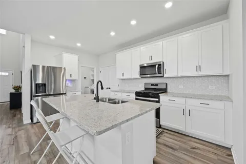 a kitchen with a sink a microwave a refrigerator and white cabinets