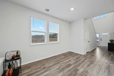 an empty room with wooden floor cabinet and windows