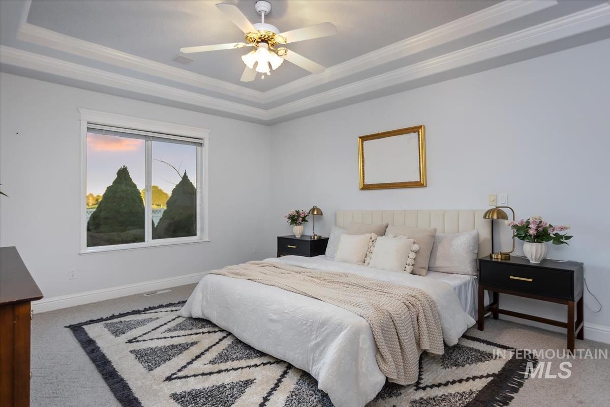 25074 The Driving Lane Caldwell, ID 83607 - Photo 11 of 29 Carpeted bedroom featuring ornamental molding, a tray ceiling, and a ceiling fan