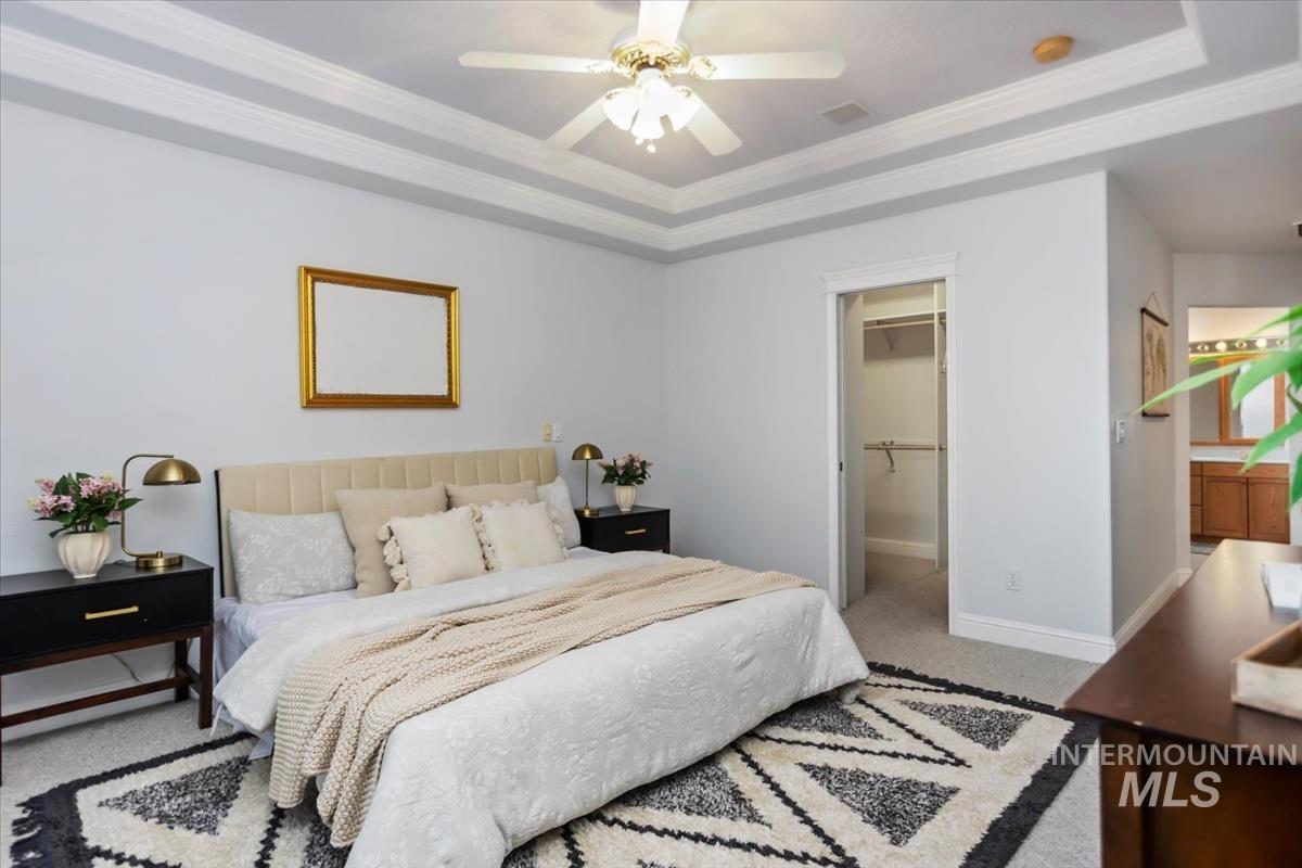 25074 The Driving Lane Caldwell, ID 83607 - Photo 13 of 29 Bedroom with light colored carpet, ornamental molding, a raised ceiling, a spacious closet, and a ceiling fan