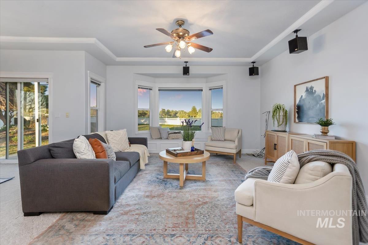 25074 The Driving Lane Caldwell, ID 83607 - Photo 9 of 29 Carpeted living room featuring a tray ceiling and ceiling fan