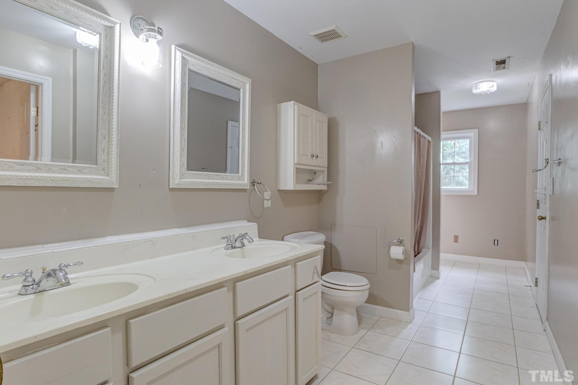 2213 East Garner Road Raleigh, NC 27610 - Photo 47 of 74 a spacious bathroom with a double vanity sink toilet and a mirror