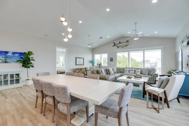 a kitchen with stainless steel appliances granite countertop a refrigerator a sink dishwasher a stove and a dining table with wooden floor