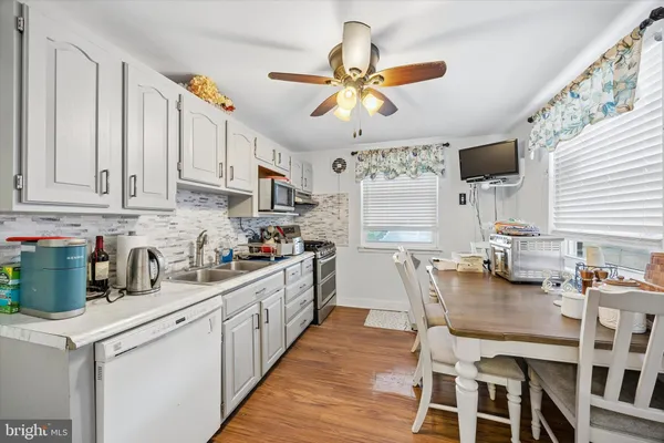 a kitchen with stainless steel appliances kitchen island granite countertop a table chairs a sink dishwasher and cabinets with wooden floor