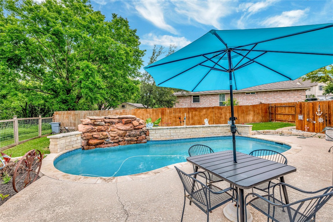 a view of pool with lawn chairs under an umbrella