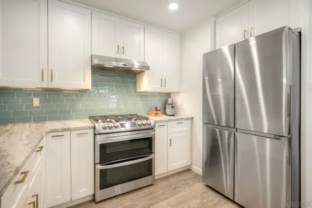 a kitchen with stainless steel appliances a refrigerator stove and cabinets