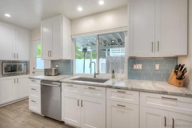 a kitchen with white cabinets and sink