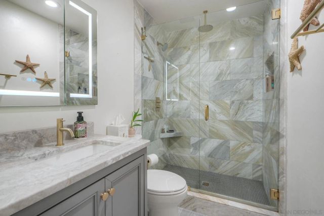 a bathroom with a granite countertop sink a toilet and shower