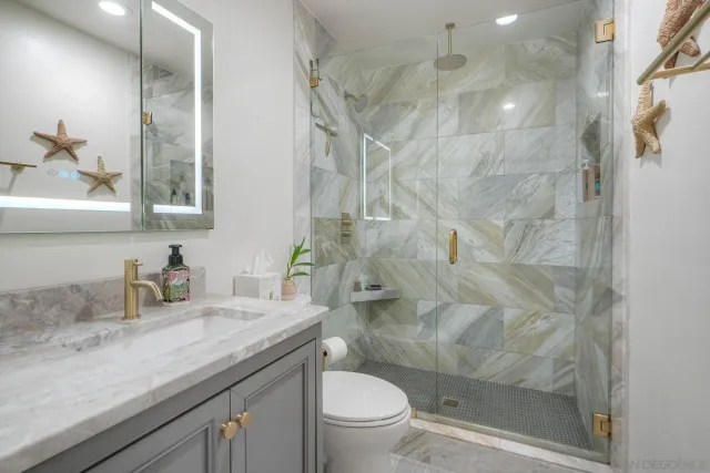 a bathroom with a granite countertop sink a toilet and shower