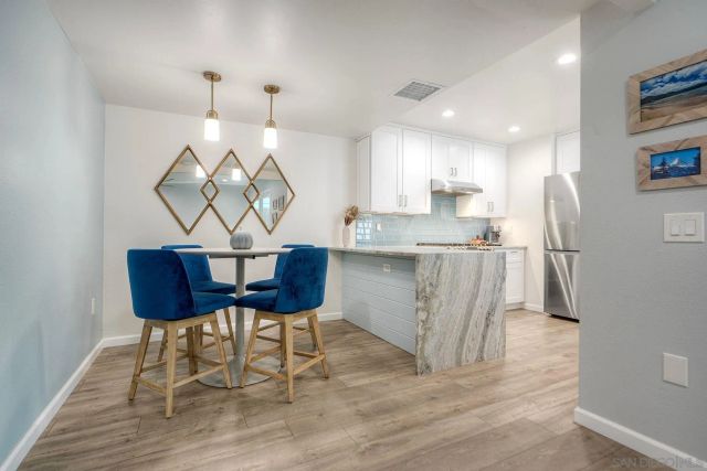 a kitchen with stainless steel appliances granite countertop a table chairs and a wooden floor