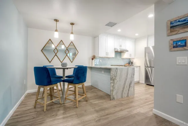 a kitchen with stainless steel appliances granite countertop a table chairs and a wooden floor